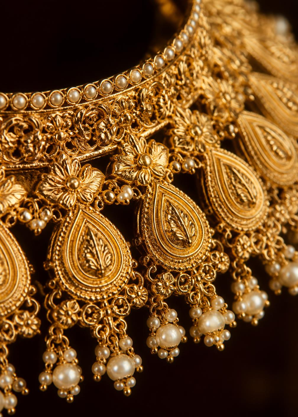 Macro detail of an intricate 21K gold bridal necklace with pearl drops